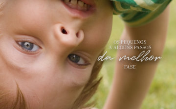 Os pequenos a alguns passos da melhor fase — criança de cabeça para baixo sorrindo no gramado.